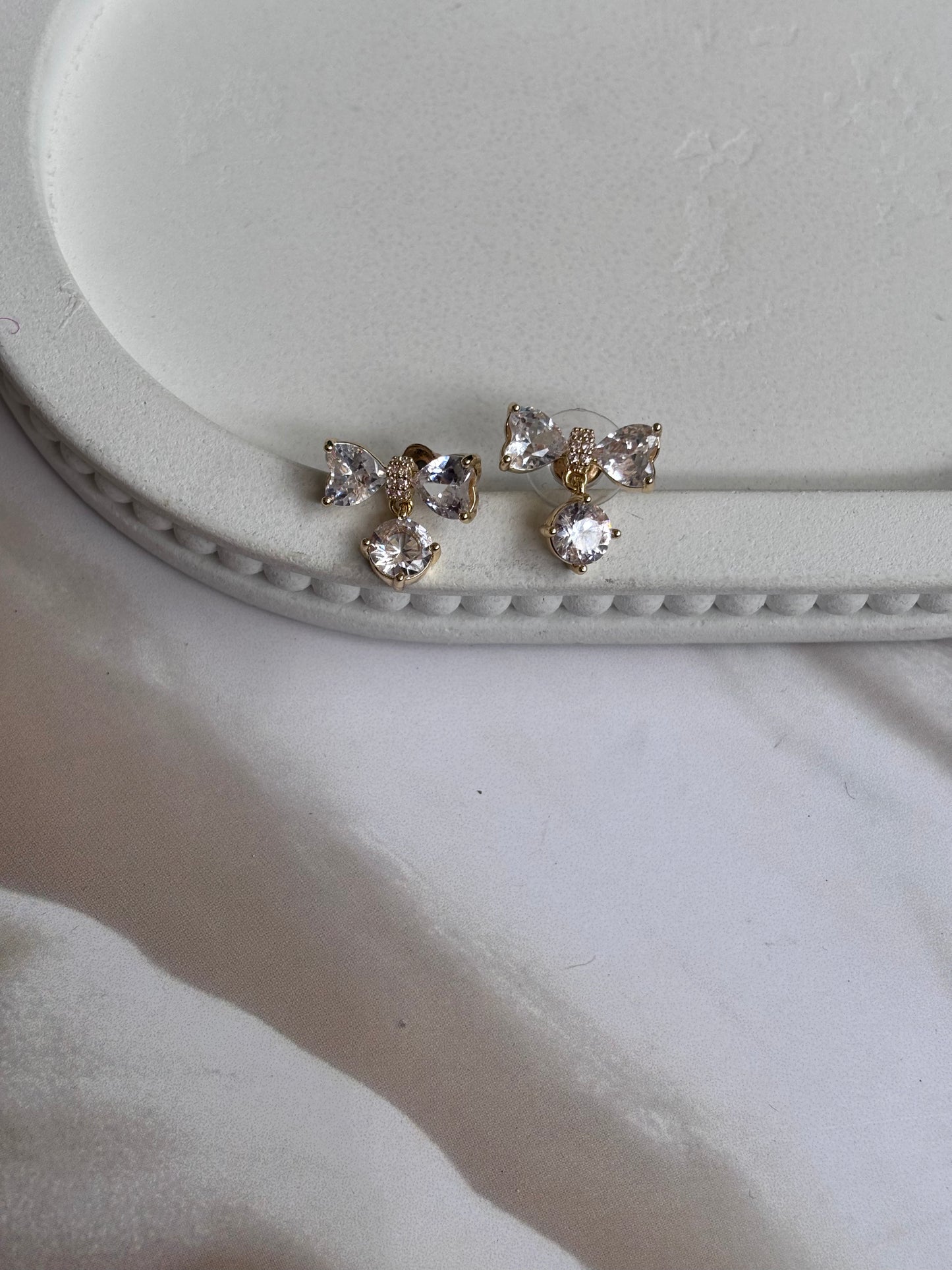 AD bow with dangling white stone studs